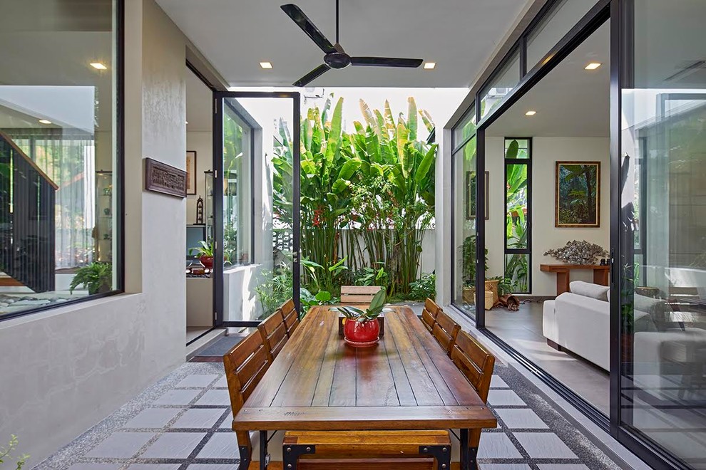 Inspiration for a tropical dining room in Singapore with white walls and concrete floors.