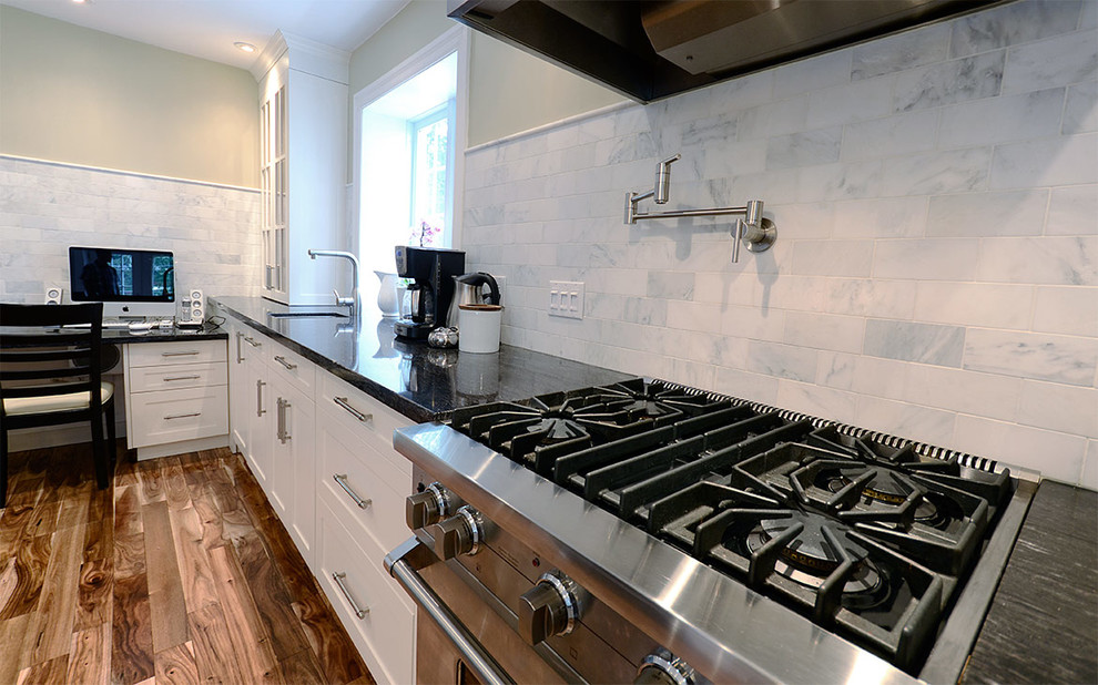 Example of a mid-sized transitional l-shaped medium tone wood floor eat-in kitchen design in Toronto with a double-bowl sink, raised-panel cabinets, white cabinets, solid surface countertops, black backsplash, stone slab backsplash, stainless steel appliances and an island