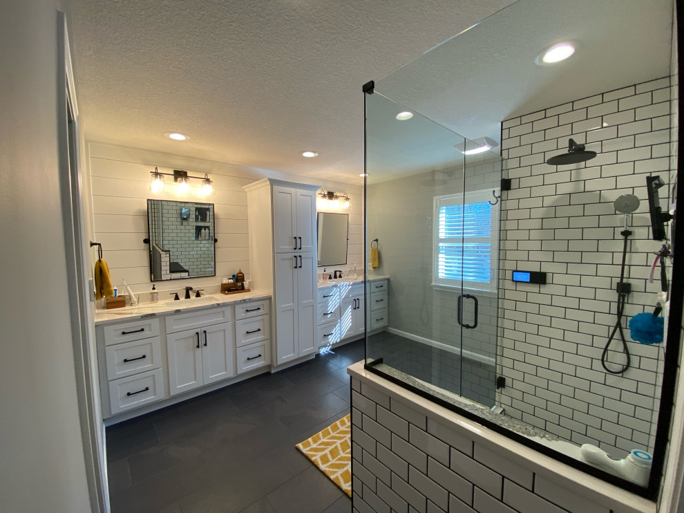 Photo of a large country master bathroom in Other with flat-panel cabinets, white cabinets, an open shower, a bidet, white tile, ceramic tile, grey walls, ceramic floors, an undermount sink, engineered quartz benchtops, black floor, a hinged shower door, white benchtops, a shower seat, a double vanity, a built-in vanity and planked wall panelling.