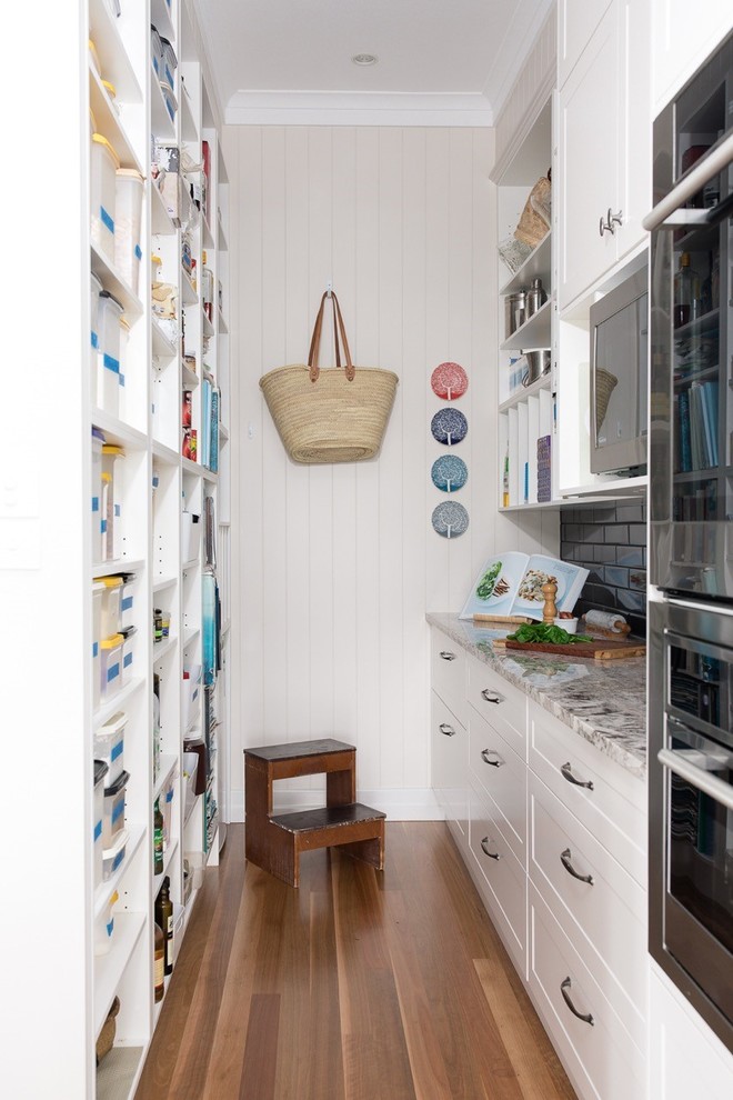 This is an example of a mid-sized contemporary kitchen in Brisbane with glass-front cabinets, white cabinets, granite benchtops, black splashback, with island and white benchtop.