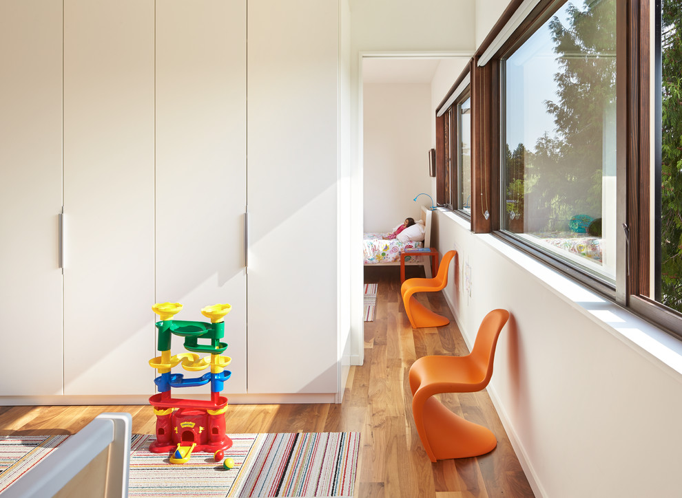 This is an example of a mid-sized modern kids' bedroom for kids 4-10 years old and girls in Seattle with white walls and medium hardwood floors.