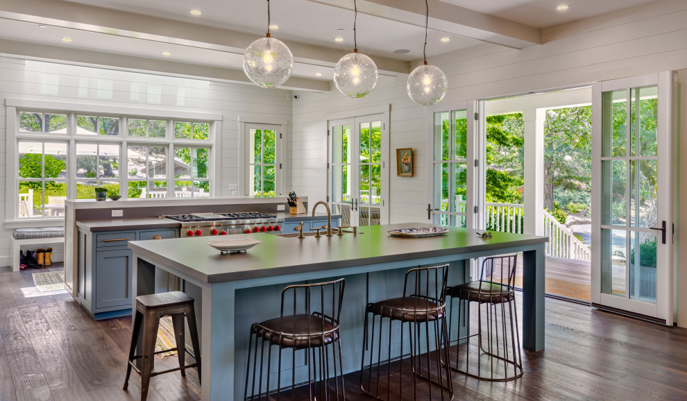 Country galley open plan kitchen in San Francisco with a farmhouse sink, shaker cabinets, blue cabinets, grey splashback, stainless steel appliances, medium hardwood floors, multiple islands, brown floor and grey benchtop.