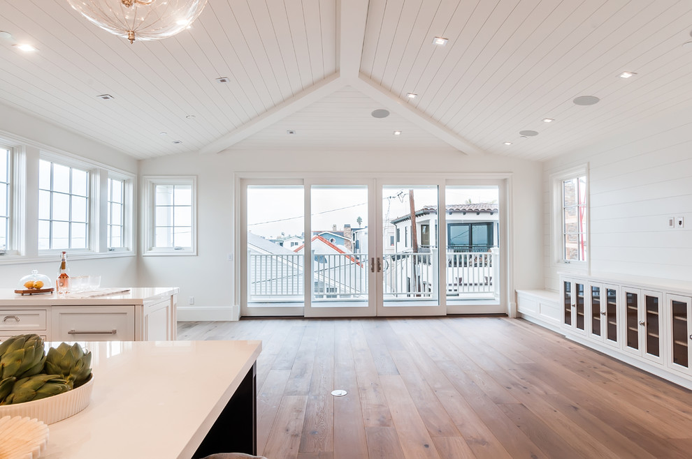 Photo of a large beach style open concept family room in San Diego with white walls and light hardwood floors.