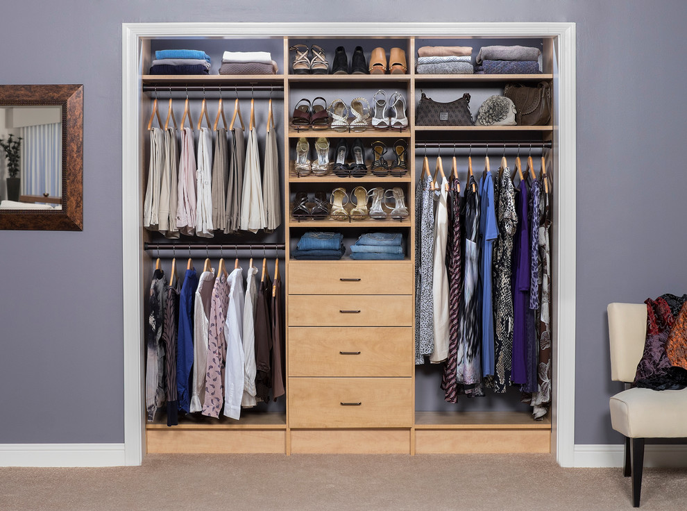 Photo of a small modern women's built-in wardrobe in New York with flat-panel cabinets, light wood cabinets and carpet.
