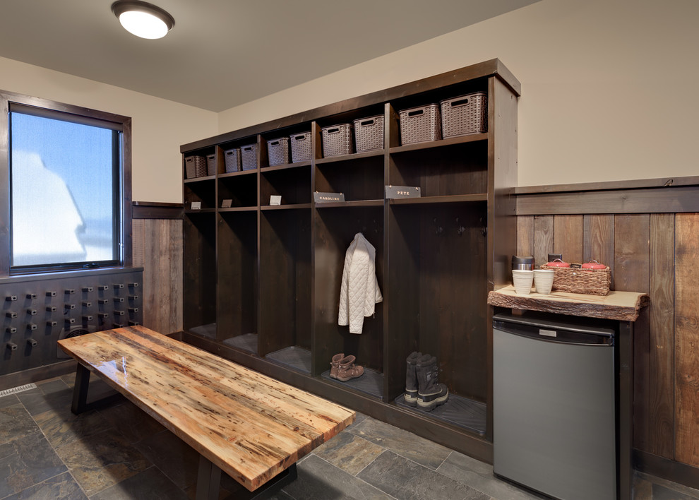 Example of a large mountain style slate floor and multicolored floor mudroom design with beige walls and a dark wood front door