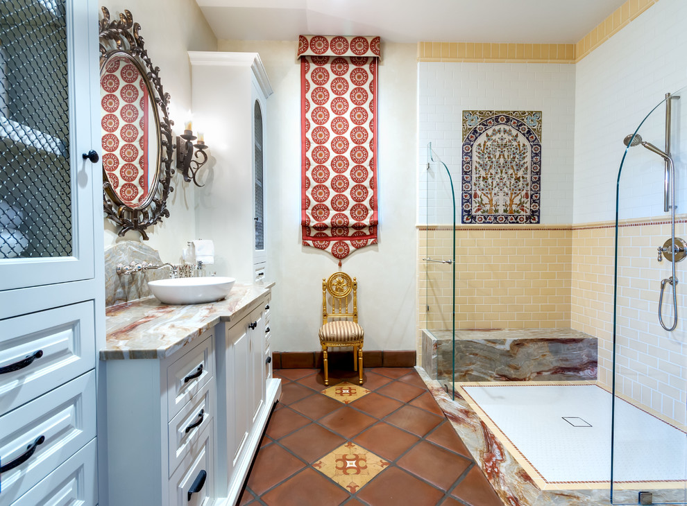 Mediterranean bathroom in San Diego with raised-panel cabinets, white cabinets, a curbless shower, white tile, yellow tile, subway tile, white walls, terra-cotta floors, a vessel sink, red floor, an open shower and multi-coloured benchtops.