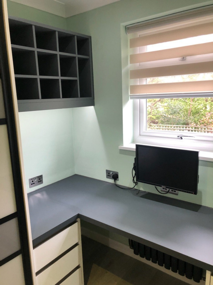 Small minimalist built-in desk light wood floor and brown floor home office photo in Surrey with green walls