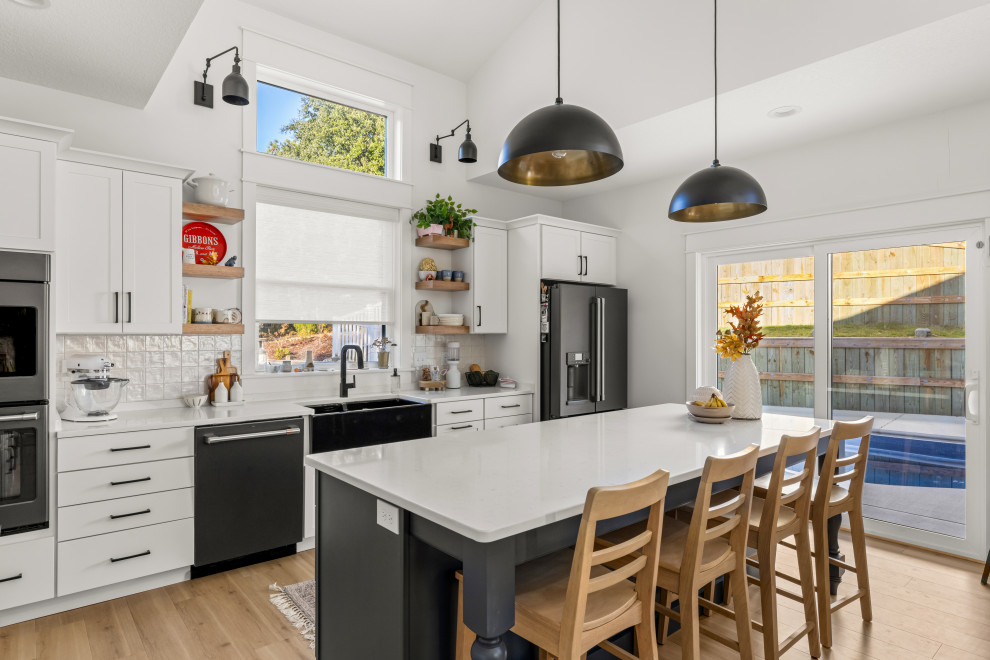 Inspiration for a modern kitchen in Other with shaker cabinets, white cabinets, white splashback, mosaic tile splashback, black appliances, light hardwood floors, with island and vaulted.