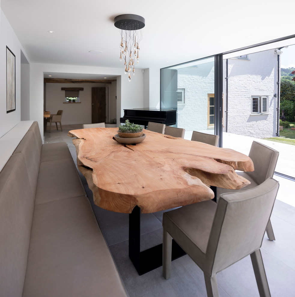 Photo of a large contemporary open plan dining in Cheshire with white walls, ceramic floors, a wood stove, a plaster fireplace surround and white floor.