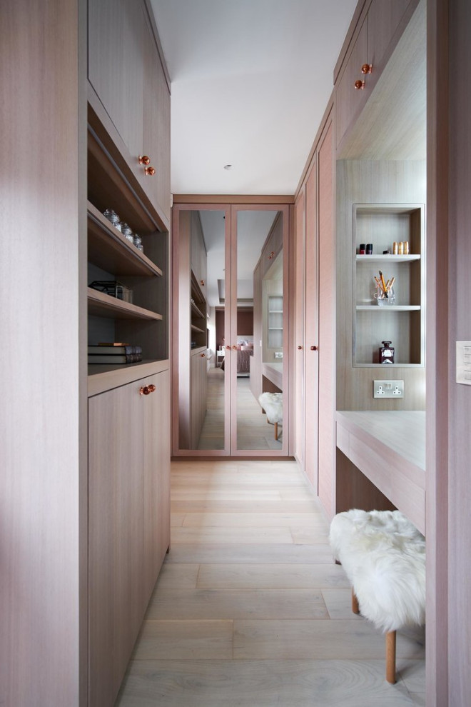 Design ideas for a small transitional women's dressing room in London with flat-panel cabinets, light wood cabinets, light hardwood floors and beige floor.