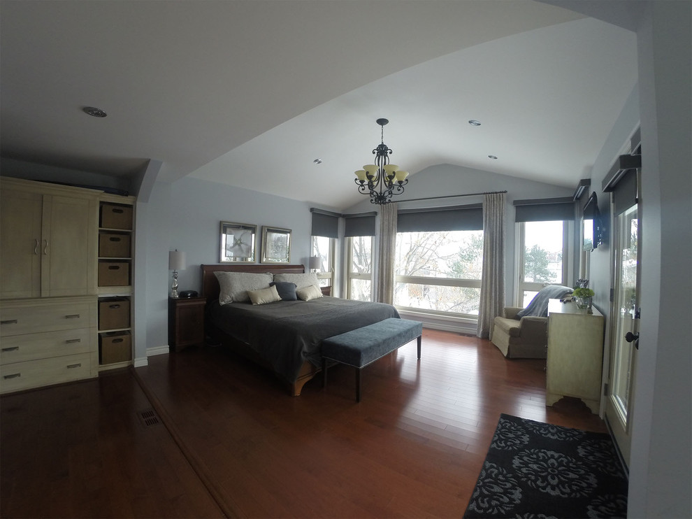 Inspiration for a large transitional master medium tone wood floor bedroom remodel in Toronto with gray walls