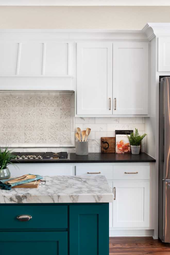 Eat-in kitchen - mid-sized transitional l-shaped light wood floor and brown floor eat-in kitchen idea in Austin with an undermount sink, white cabinets, granite countertops, white backsplash, stainless steel appliances, an island and multicolored countertops