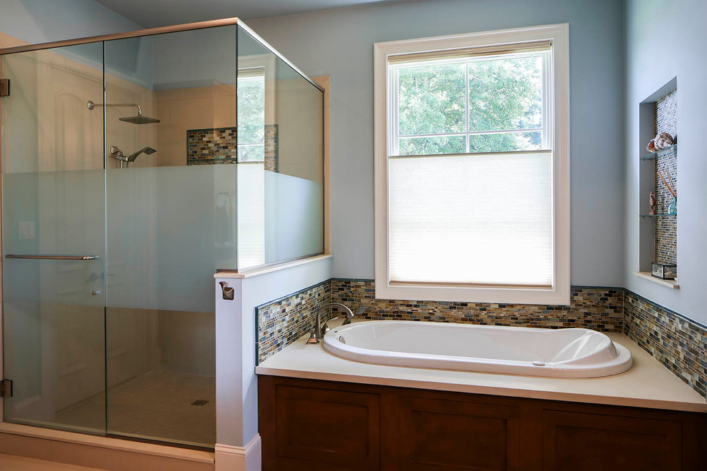 Inspiration for a mid-sized transitional bathroom in New Orleans with shaker cabinets, medium wood cabinets, engineered quartz benchtops, a drop-in tub, blue tile, mosaic tile, blue walls and porcelain floors.