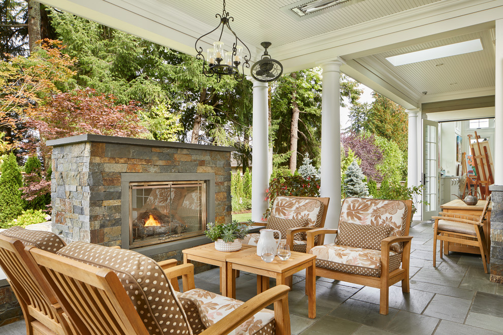 Example of a classic tile patio design in Seattle with a fireplace and a roof extension
