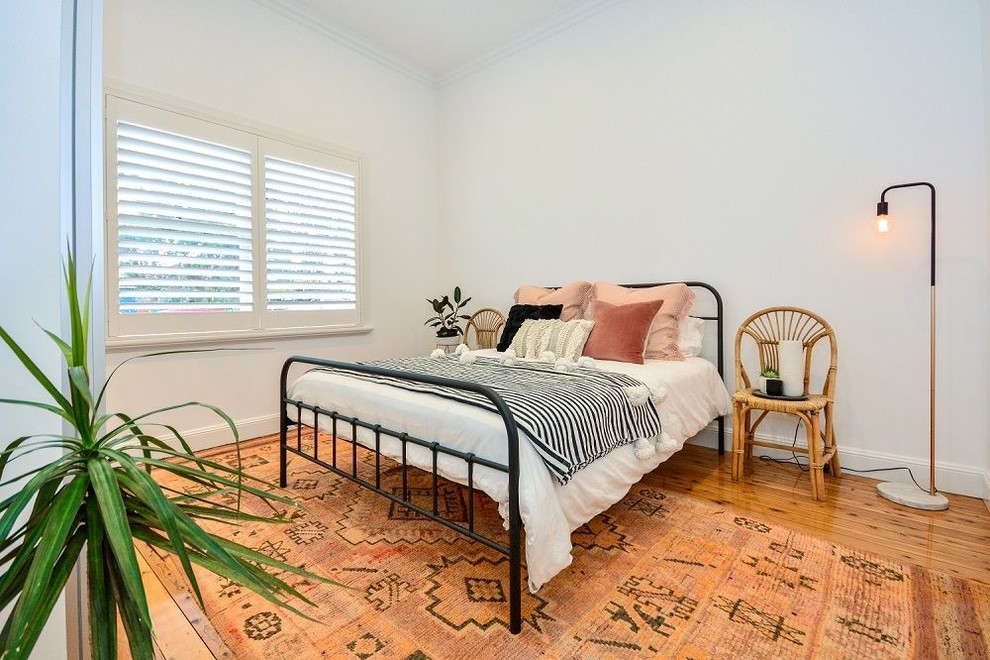 Photo of a transitional guest bedroom in Brisbane with white walls, medium hardwood floors and brown floor.