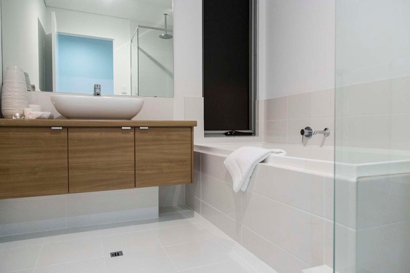 Design ideas for a mid-sized contemporary bathroom in Perth with a vessel sink, flat-panel cabinets, medium wood cabinets, laminate benchtops, a drop-in tub, white tile, ceramic tile, white walls and porcelain floors.