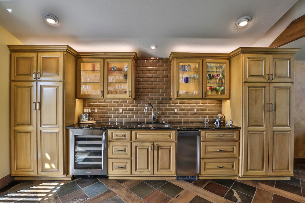 This is an example of a large country l-shaped eat-in kitchen in Seattle with an undermount sink, light wood cabinets, solid surface benchtops, brown splashback, glass tile splashback, stainless steel appliances, with island, beaded inset cabinets, medium hardwood floors and brown floor.