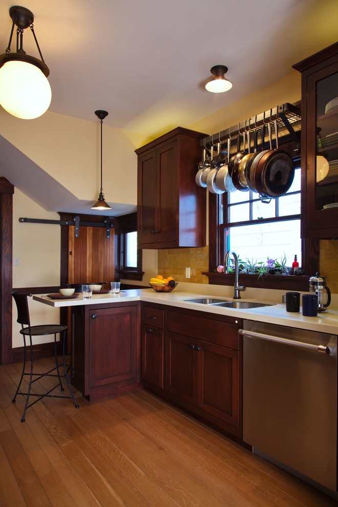 Inspiration for a mid-sized arts and crafts galley separate kitchen in San Francisco with a double-bowl sink, shaker cabinets, dark wood cabinets, quartz benchtops, beige splashback, travertine splashback, stainless steel appliances, medium hardwood floors and brown floor.