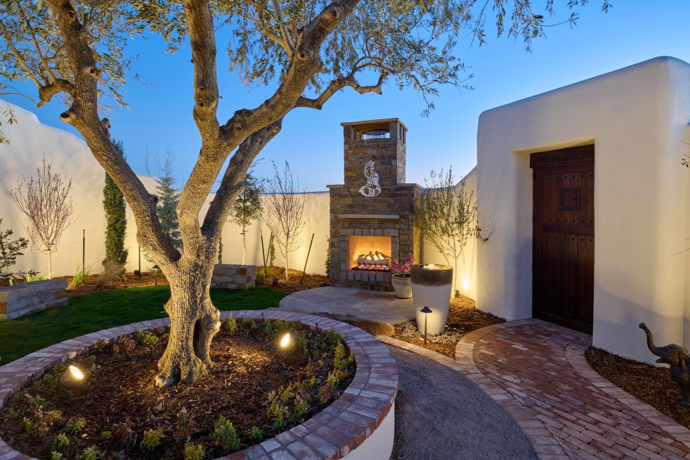 This is an example of a mid-sized eclectic courtyard xeriscape in Other with with fireplace and brick pavers.
