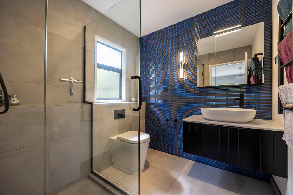 Design ideas for a small contemporary master bathroom in Auckland with shaker cabinets, black cabinets, a corner shower, a one-piece toilet, blue tile, ceramic tile, grey walls, cement tiles, a vessel sink, engineered quartz benchtops, grey floor, a hinged shower door, white benchtops, a niche, a single vanity and a floating vanity.