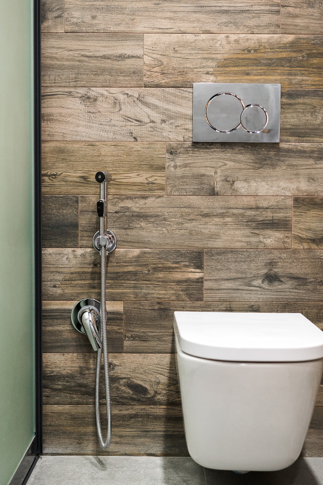 Inspiration for a mid-sized industrial 3/4 bathroom in Other with glass-front cabinets, dark wood cabinets, a curbless shower, a wall-mount toilet, brown tile, porcelain tile, grey walls, porcelain floors, a drop-in sink, tile benchtops, grey floor and a hinged shower door.