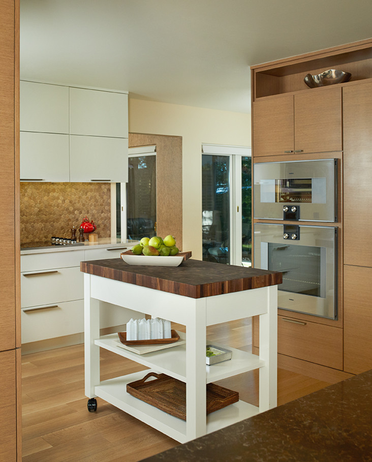 Eat-in kitchen - large transitional u-shaped light wood floor and beige floor eat-in kitchen idea with an undermount sink, flat-panel cabinets, granite countertops, beige backsplash, mosaic tile backsplash, paneled appliances, an island, black countertops and medium tone wood cabinets