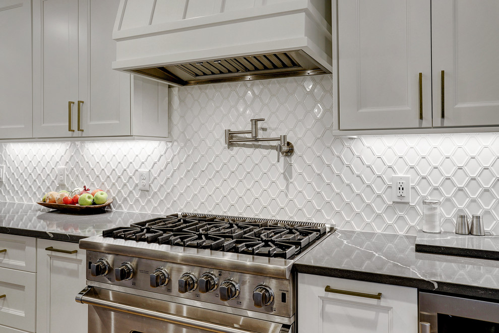 Mid-sized transitional galley light wood floor and yellow floor eat-in kitchen photo in Houston with a farmhouse sink, recessed-panel cabinets, white cabinets, quartz countertops, white backsplash, ceramic backsplash, stainless steel appliances, an island and white countertops
