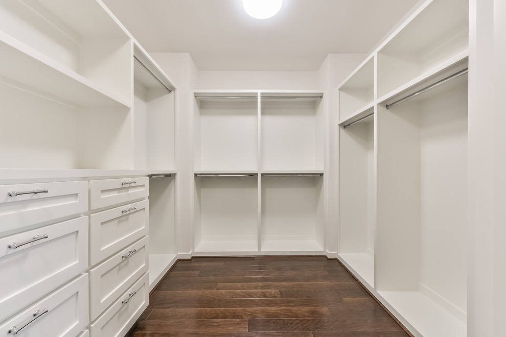 Mid-sized walk-in wardrobe in Houston with shaker cabinets, white cabinets and dark hardwood floors.