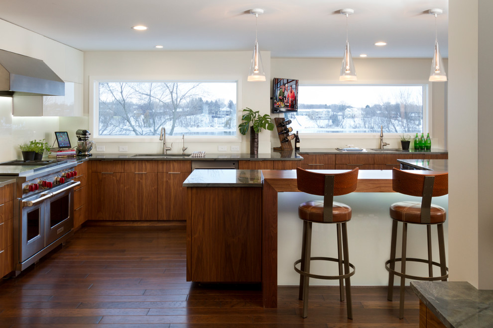 Photo of a large contemporary l-shaped eat-in kitchen in Minneapolis with an undermount sink, flat-panel cabinets, medium wood cabinets, granite benchtops, white splashback, glass sheet splashback, stainless steel appliances, dark hardwood floors and with island.