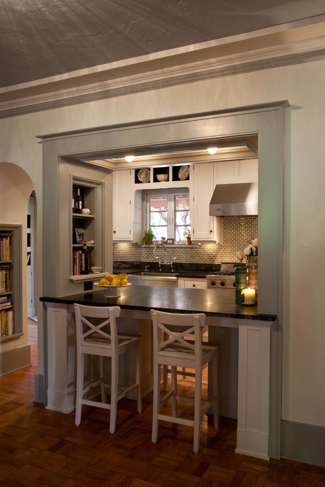 Inspiration for a mid-sized traditional galley separate kitchen in Miami with a farmhouse sink, shaker cabinets, white cabinets, soapstone benchtops, grey splashback, glass tile splashback, stainless steel appliances, light hardwood floors and no island.