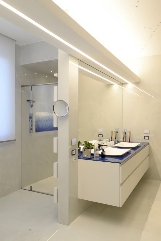 Inspiration för moderna blått badrum, med vita skåp, en kantlös dusch, beige kakel, vita väggar och vitt golv