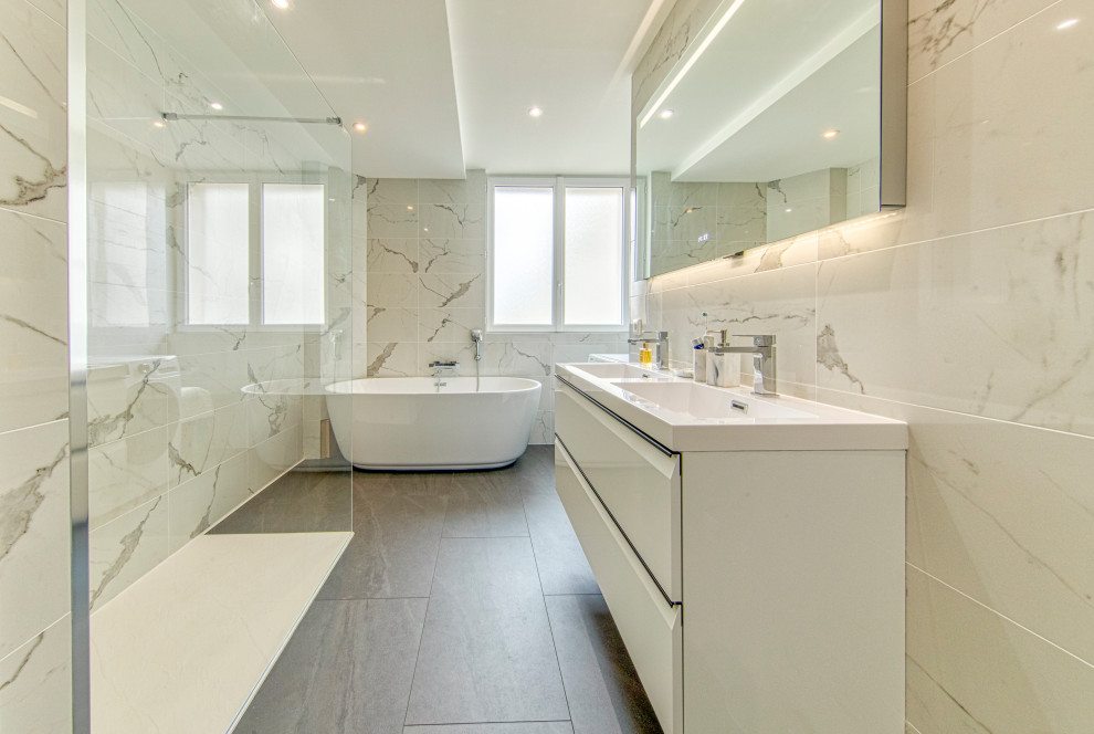 Пример оригинального дизайна: ванная комната в стиле модернизм с белыми фасадами, открытым душем, раздельным унитазом, белой плиткой, мраморной плиткой, душевой кабиной, настольной раковиной, серым полом, открытым душем, окном, тумбой под две раковины и подвесной тумбой
