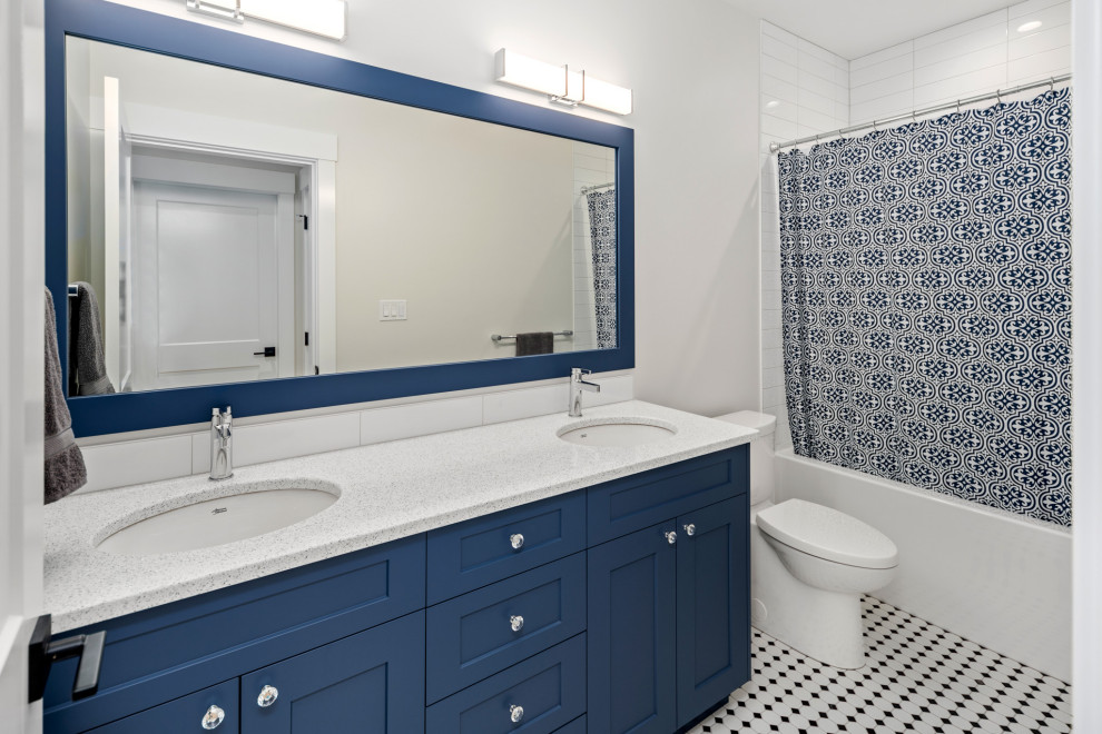 This is an example of a mid-sized country kids bathroom in Vancouver with shaker cabinets, blue cabinets, a shower/bathtub combo, a one-piece toilet, white tile, subway tile, grey walls, porcelain floors, a drop-in sink, engineered quartz benchtops, white floor, a shower curtain, grey benchtops, a double vanity and a built-in vanity.