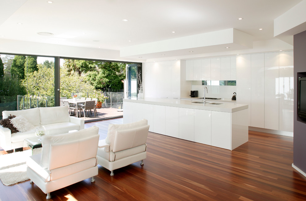 Design ideas for a modern galley eat-in kitchen in Sydney with flat-panel cabinets, white cabinets, quartz benchtops, white splashback, glass tile splashback, stainless steel appliances, medium hardwood floors and with island.