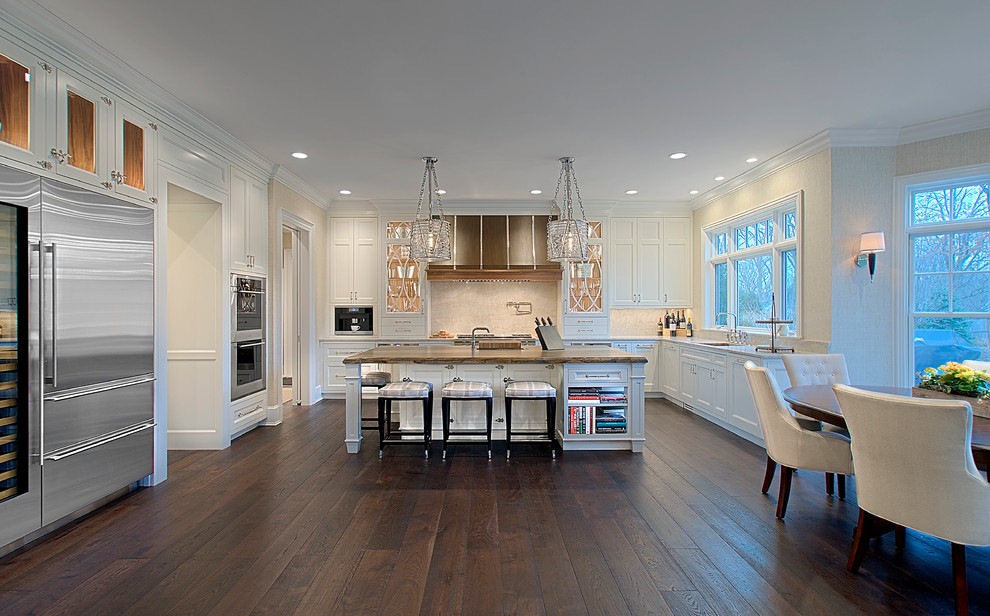 Huge transitional u-shaped dark wood floor and brown floor open concept kitchen photo in Chicago with stainless steel appliances, an island, shaker cabinets, white cabinets, beige backsplash, stone slab backsplash, quartzite countertops and white countertops