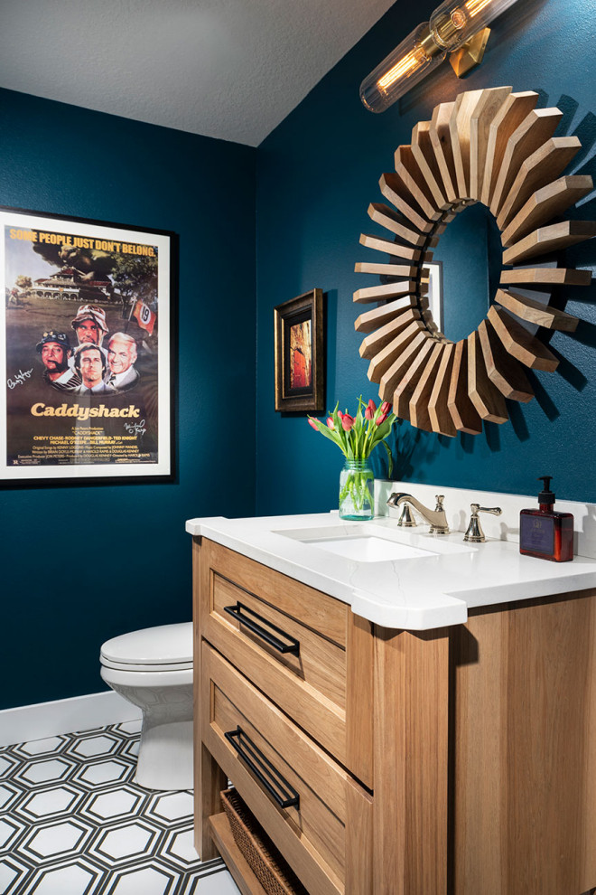 Klassisk inredning av ett mellanstort vit vitt toalett, med skåp i ljust trä, blå väggar, klinkergolv i porslin, ett undermonterad handfat och bänkskiva i kvartsit