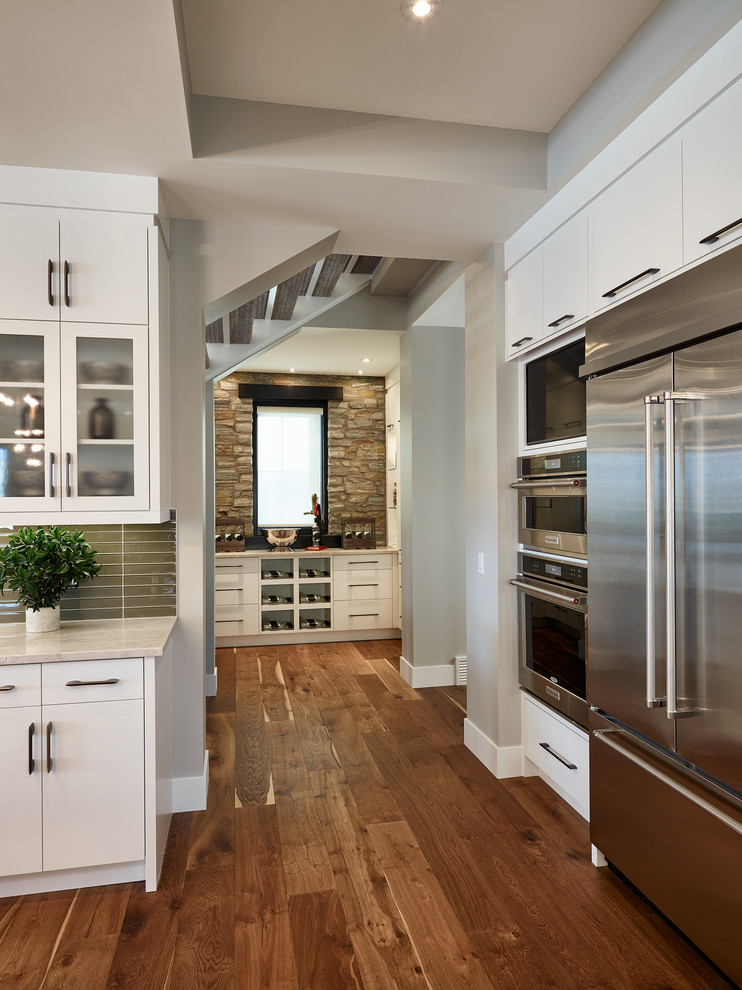 Inspiration for a huge transitional medium tone wood floor kitchen pantry remodel in Calgary with flat-panel cabinets, white cabinets and glass tile backsplash