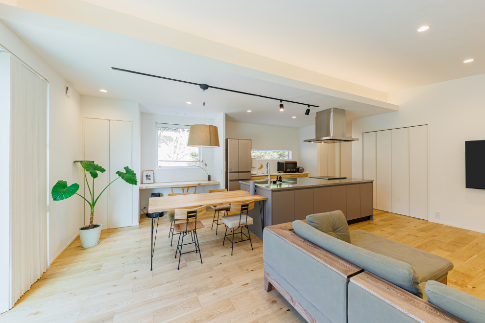 Photo of a mid-sized modern single-wall open plan kitchen in Kobe with an integrated sink, flat-panel cabinets, medium wood cabinets, grey splashback, medium hardwood floors, with island, brown floor and wallpaper.