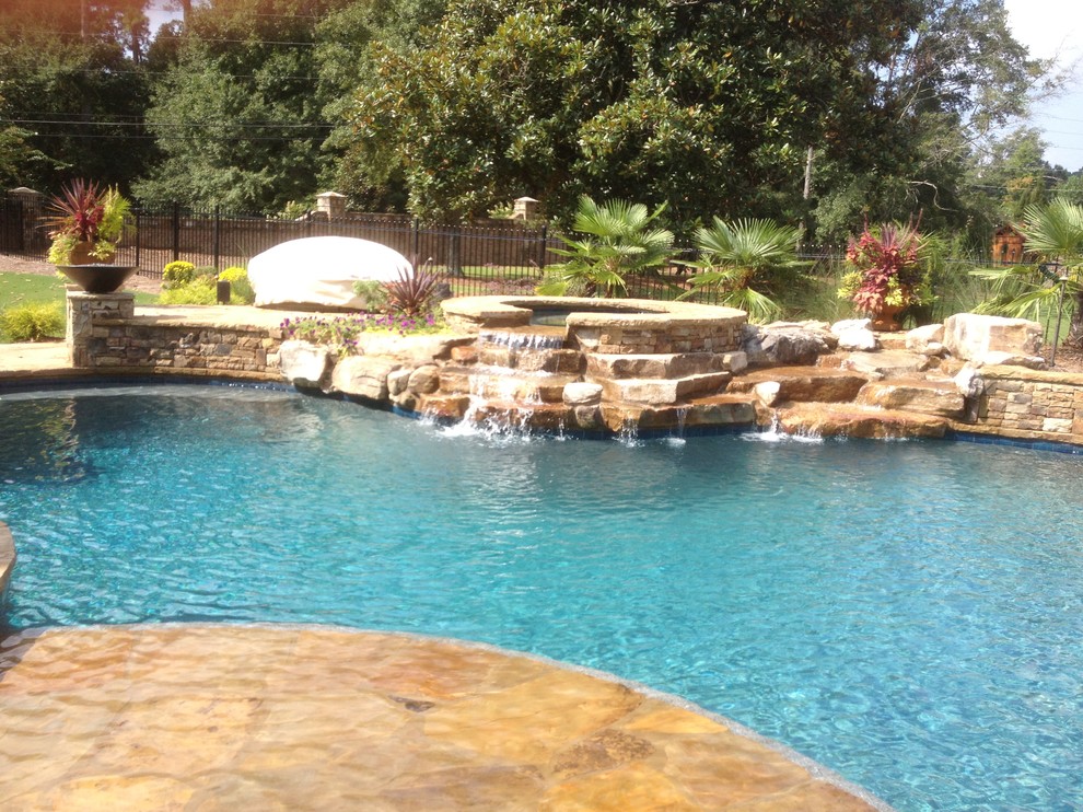 Large transitional backyard custom-shaped lap pool in Atlanta with a water feature and natural stone pavers.