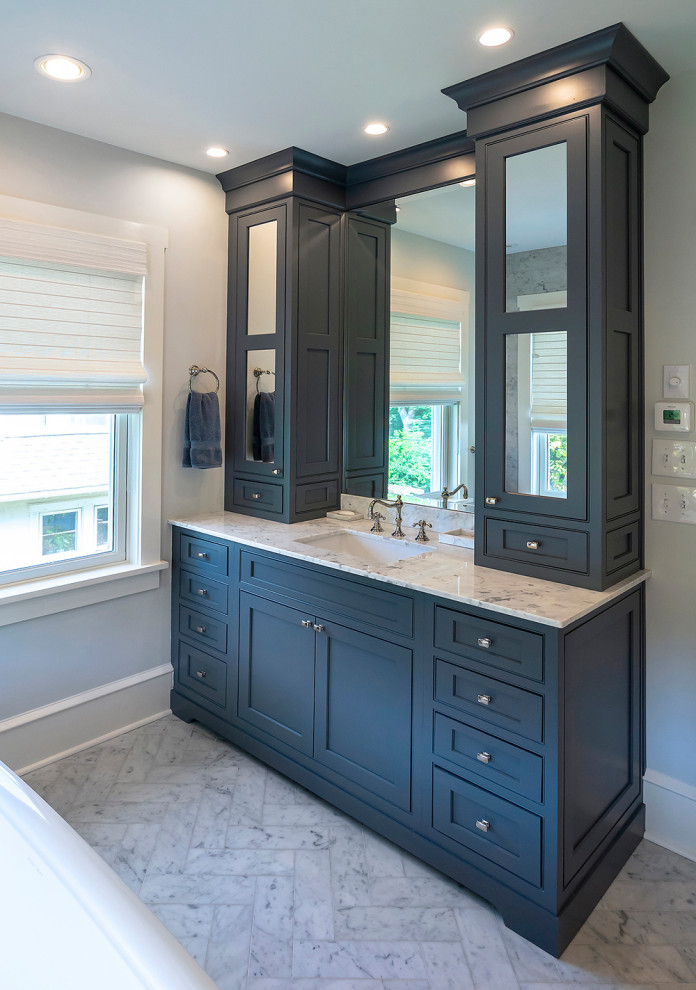 Design ideas for a mid-sized arts and crafts bathroom in Philadelphia with beaded inset cabinets, blue cabinets, a freestanding tub, a double shower, white tile, marble, grey walls, marble floors, an undermount sink, marble benchtops, white floor, a hinged shower door and white benchtops.