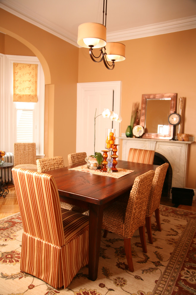 Inspiration for a traditional dining room in Boston with orange walls, medium hardwood floors and a standard fireplace.
