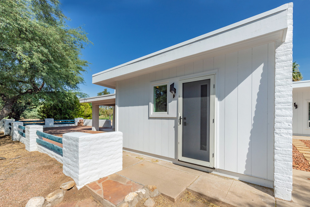 Photo of a medium sized and white retro bungalow side detached house in Phoenix with concrete fibreboard cladding, a flat roof and a white roof.