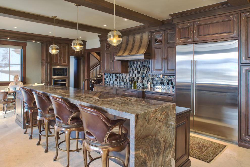 This is an example of a traditional galley open plan kitchen in Denver with an undermount sink, beaded inset cabinets, medium wood cabinets, granite benchtops, blue splashback, metal splashback, stainless steel appliances, limestone floors, with island, white floor, multi-coloured benchtop and exposed beam.