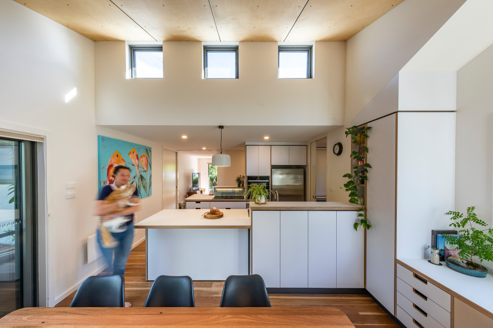 This is an example of a medium sized scandi galley kitchen/diner in Canberra - Queanbeyan with laminate countertops, ceramic splashback, light hardwood flooring, white worktops and a timber clad ceiling.