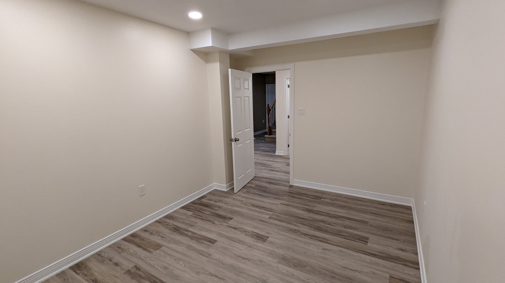 Inspiration for a mid-sized transitional basement in Ottawa with white walls, laminate floors, no fireplace and brown floor.