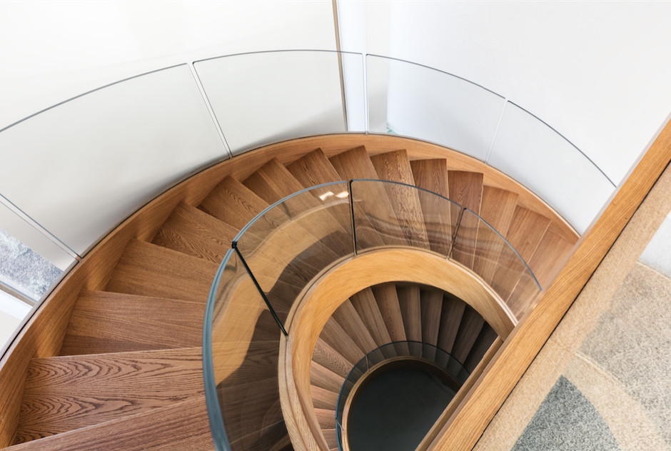 This is an example of a contemporary wood curved glass railing staircase in Munich with open risers.