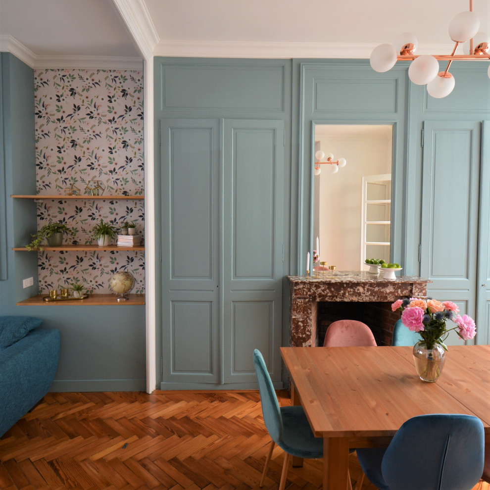 Inspiration pour une grande salle à manger ouverte sur le salon traditionnelle avec un mur bleu, un sol en bois brun, une cheminée standard, un manteau de cheminée en pierre, un sol marron et boiseries.