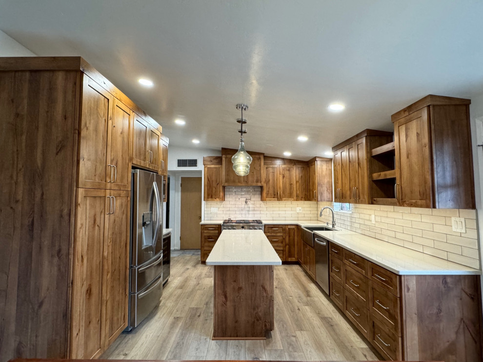 Eat-in kitchen - mid-sized transitional u-shaped laminate floor and beige floor eat-in kitchen idea in Phoenix with a farmhouse sink, shaker cabinets, medium tone wood cabinets, quartz countertops, white backsplash, porcelain backsplash, stainless steel appliances, an island and beige countertops