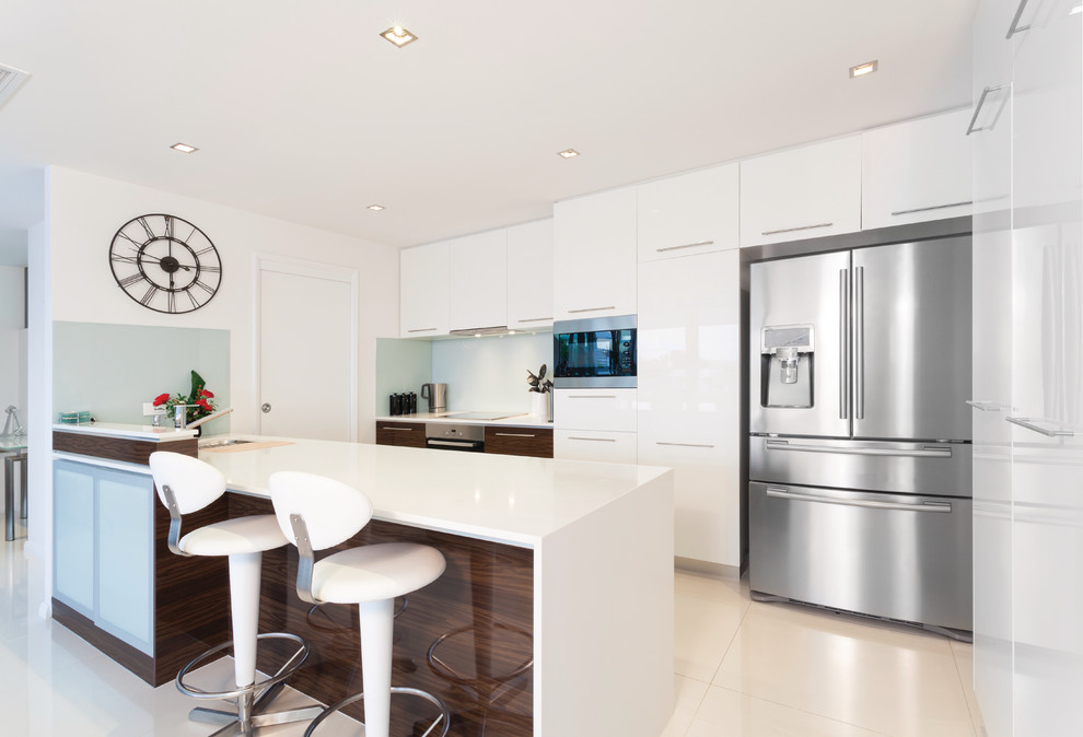 Inspiration for a mid-sized contemporary single-wall open plan kitchen in Other with flat-panel cabinets, white cabinets, white splashback, stainless steel appliances and a peninsula.