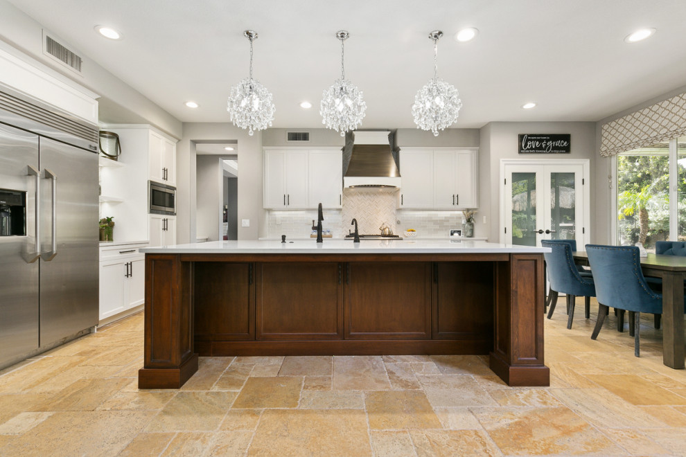 Example of a huge transitional u-shaped travertine floor and beige floor open concept kitchen design in Orange County with a single-bowl sink, shaker cabinets, white cabinets, quartz countertops, multicolored backsplash, stone tile backsplash, stainless steel appliances, an island and white countertops